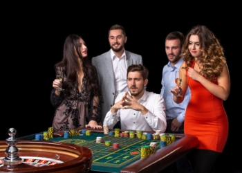 Group of young people looking excited at spinning roulette. Roulette table in a casino. Black background
