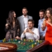 Group of young people looking excited at spinning roulette. Roulette table in a casino. Black background